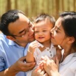 Sleep - Loving parents and baby embracing and kissing on cheek at park