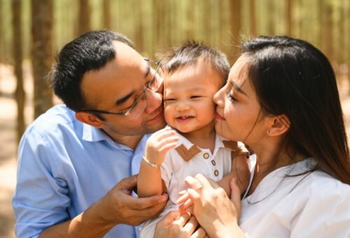Sleep - Loving parents and baby embracing and kissing on cheek at park