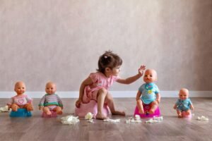 The girl is sitting on the potty with her dolls.