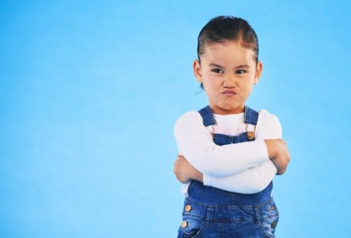 Angry, child and arms crossed with tantrum in studio with mockup space. Kid, young girl and frustra