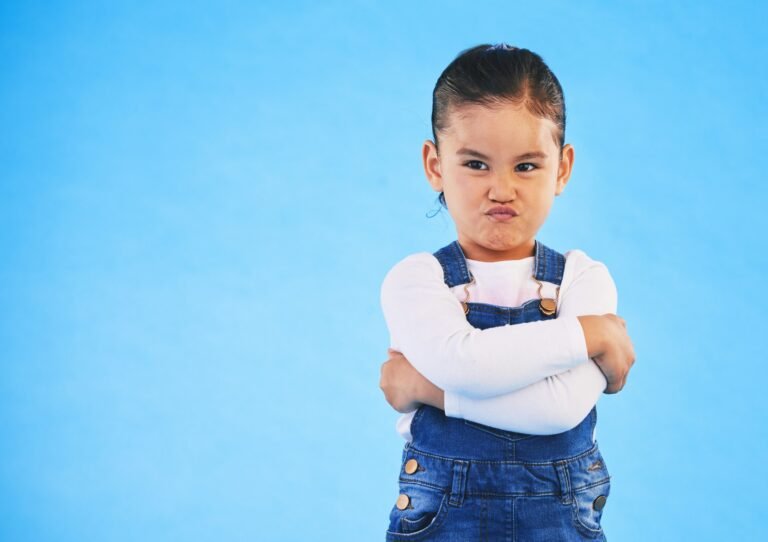 Angry, child and arms crossed with tantrum in studio with mockup space. Kid, young girl and frustra