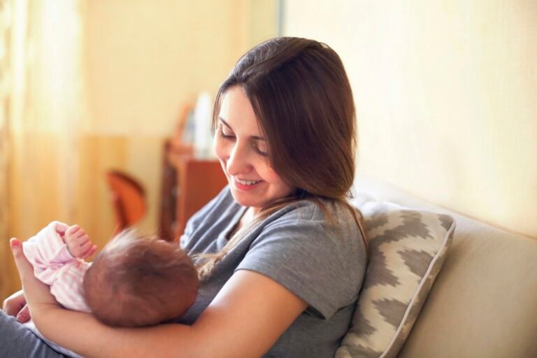 Young mother holding her newborn child. Mom nursing baby.